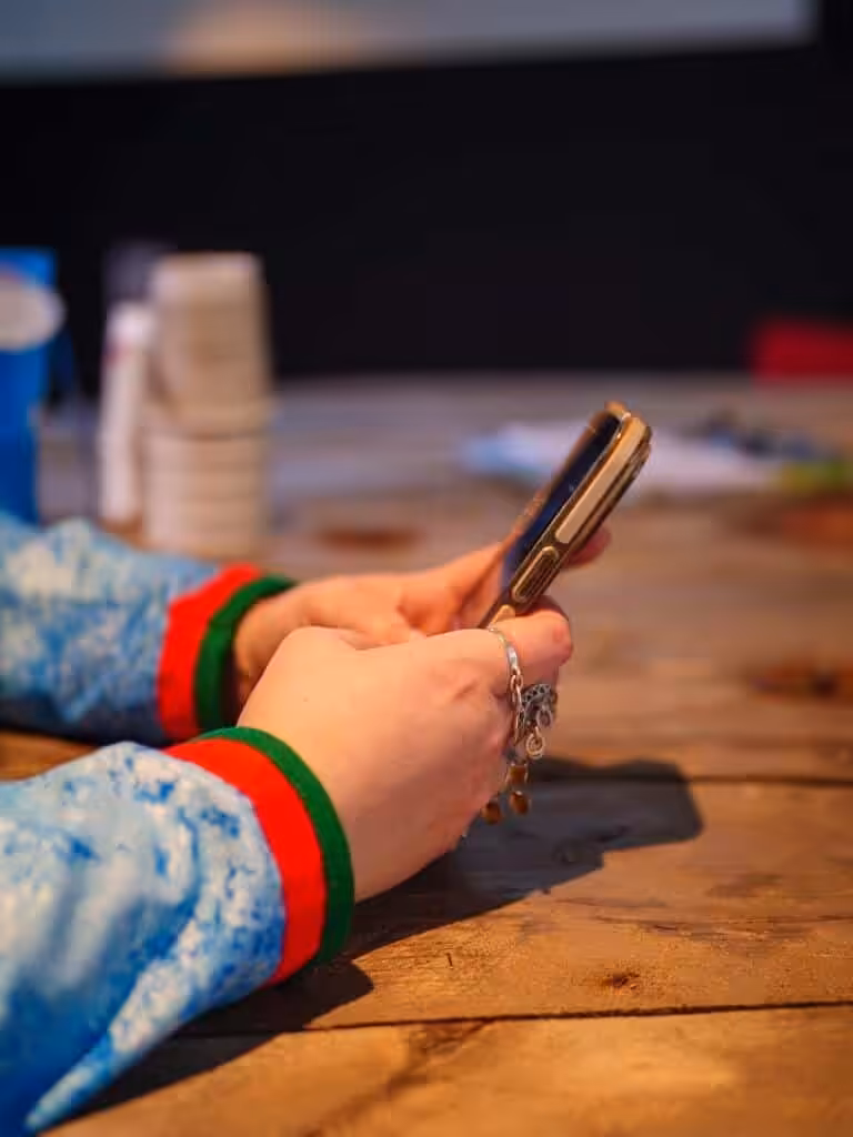 Nærbilde av en samisk kvinnes hender med mobiltelefon