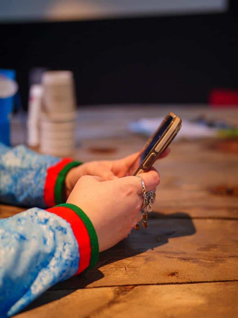 Nærbilde av en samisk kvinnes hender med mobiltelefon