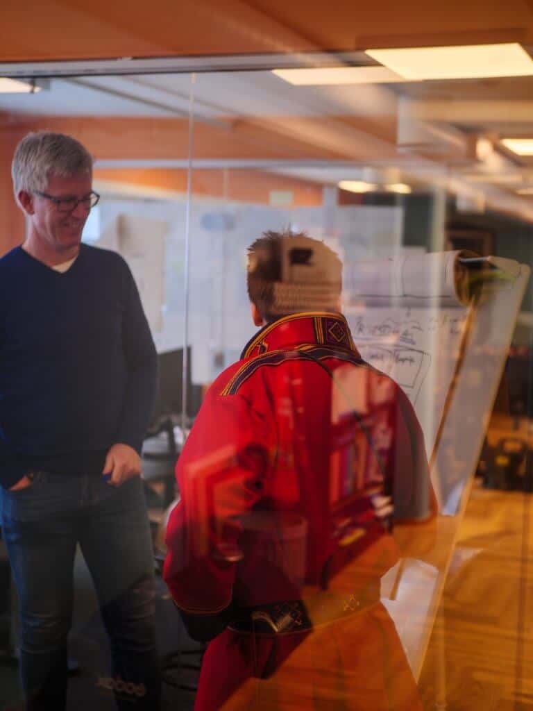 Bildet viser en faglig diskusjon, med en samisk mannlig person som snakker med en norsk person.