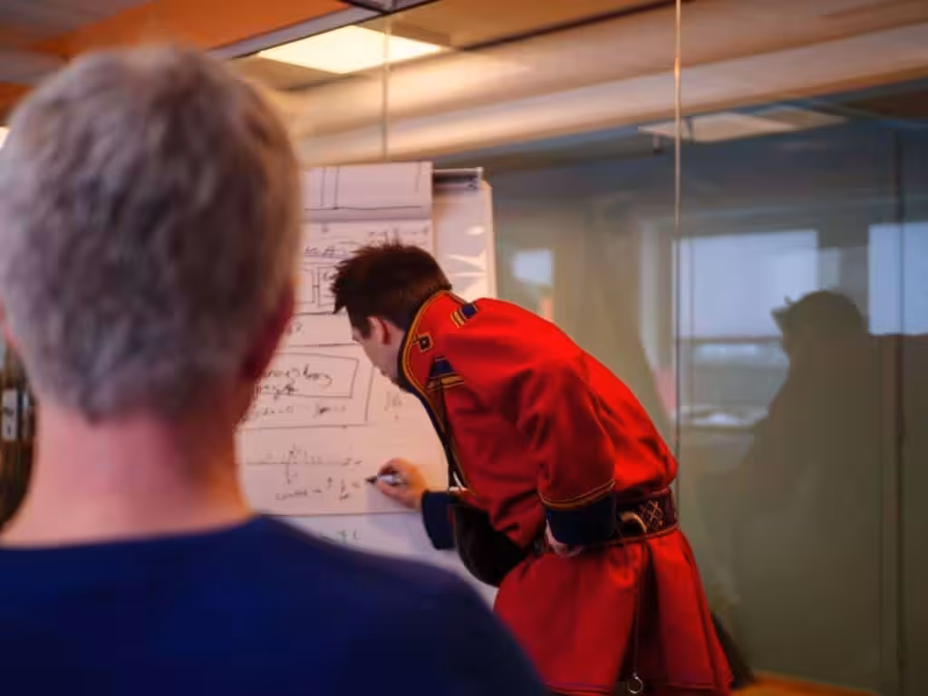 En samisk mann forklarer med tusj i en presentasjon for andre