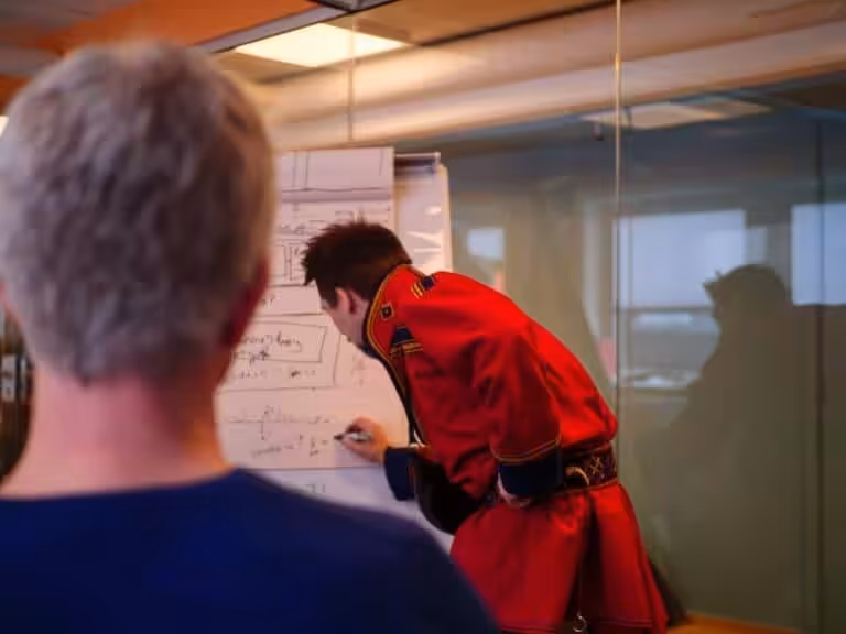 En samisk mann forklarer med tusj i en presentasjon for andre