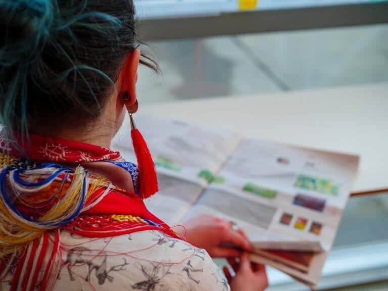 Bildet viser en samisk kvinne som leser i en tradisjonell papiravis.