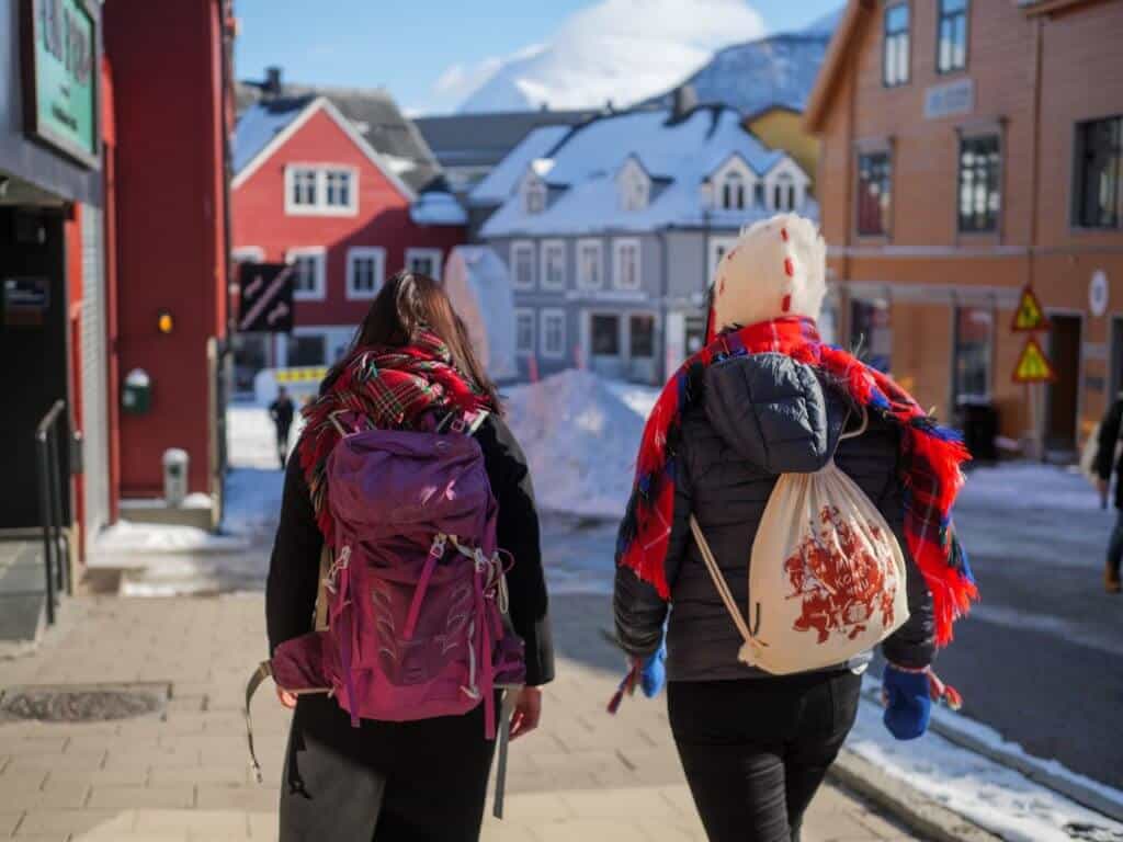 Bildet viser to samiske kvinner sett bakfra som går nedover en gate i Tromsø